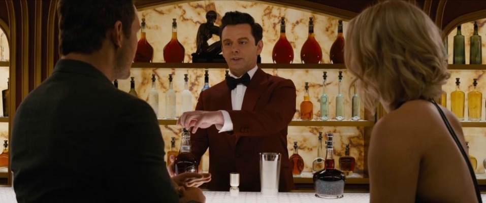 Chris Pratt and Jennifer Lawrence talking with a robotic bartender played by Michael Sheen at a bar on the Starship Avalon in the movie Passengers Photo courtesy of Columbia Pictures 2