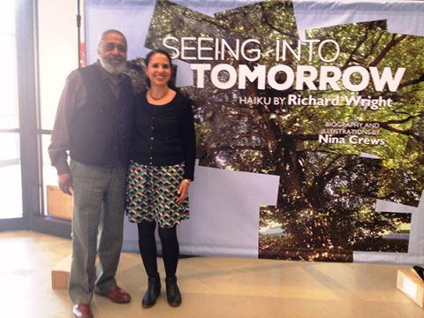 Nina Crews (r), with her father, Donald Crews, standing in front of a sign depicting her book, Seeing Into Tomorrow: Haiku by Richard Wright